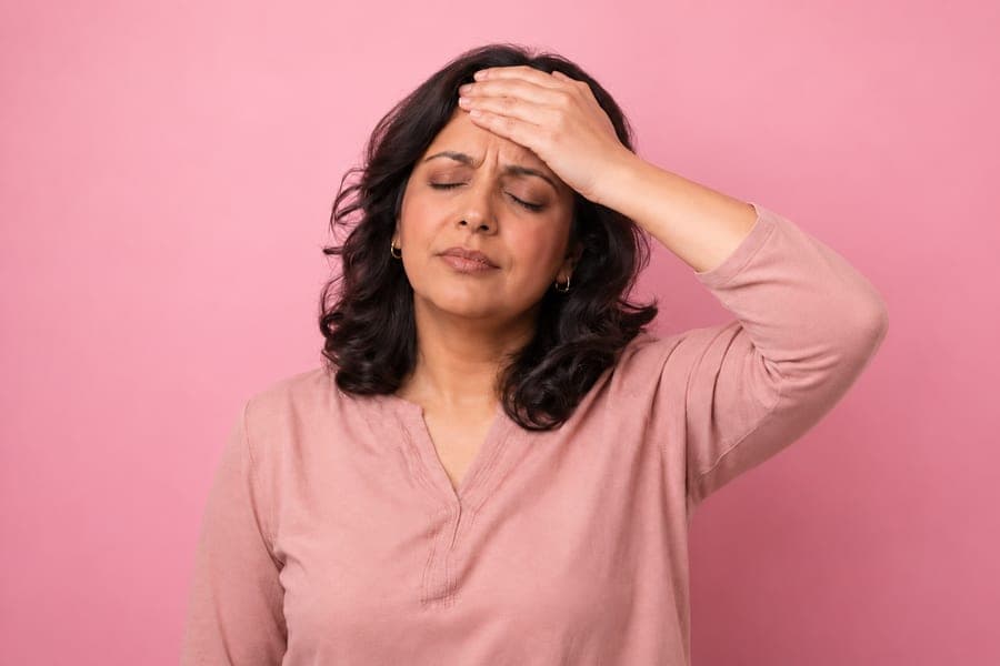 Woman with her eyes closed and a hand on her forehead, feeling overheated